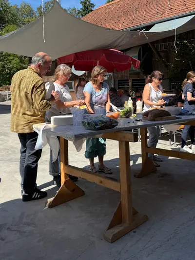 Langer gedeckter Tisch im Hof, Gäste beim Essen unter dem Sonnenschirm