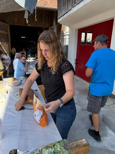 Frau trägt Brot vom Buffet, im Hintergrund die rote Scheunentür