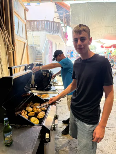 Junger Mann am Grill, davor das Grillgut auf dem Rost
