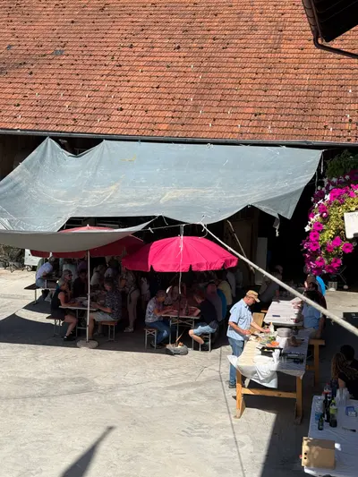 Der Hof mit rotem Schirm und Blumenkasten, Gäste an den Tischen